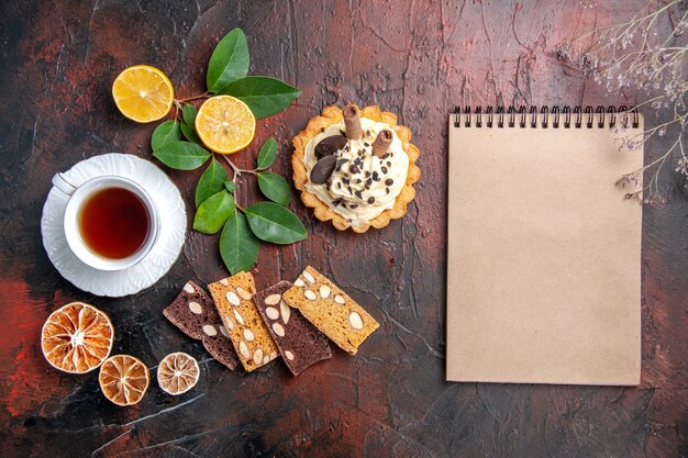 Draufsicht köstlicher cremiger Kuchen mit Tasse Tee auf dem dunklen Tisch süßer Kuchen Nachtisch