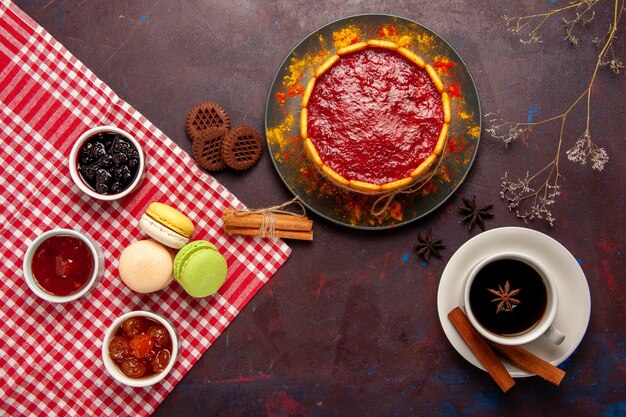 Draufsicht köstlicher Dessertkuchen mit Tasse Kaffee und Fruchtmarmeladen auf dunklem Schreibtischkekszuckerplätzchenkuchendessert süß