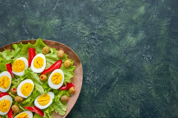 Draufsicht köstlicher Eiersalat mit grünem Salat und Oliven auf dunkelblauem Hintergrund