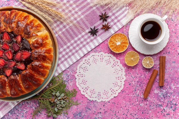 Draufsicht köstlicher Erdbeerkuchen fruchtiger Kuchen mit Tasse Tee auf dem Rosa