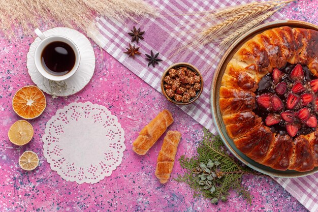 Draufsicht köstlicher Erdbeerkuchen fruchtiger Kuchen mit Tasse Tee auf hellrosa