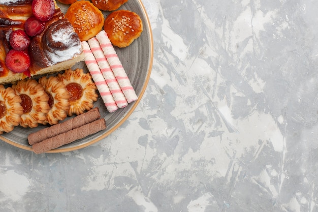 Draufsicht köstlicher Erdbeerkuchen mit Keksen und kleinen Kuchen auf hellweißem Hintergrundkekszuckerkuchen süßer Kuchenplätzchen