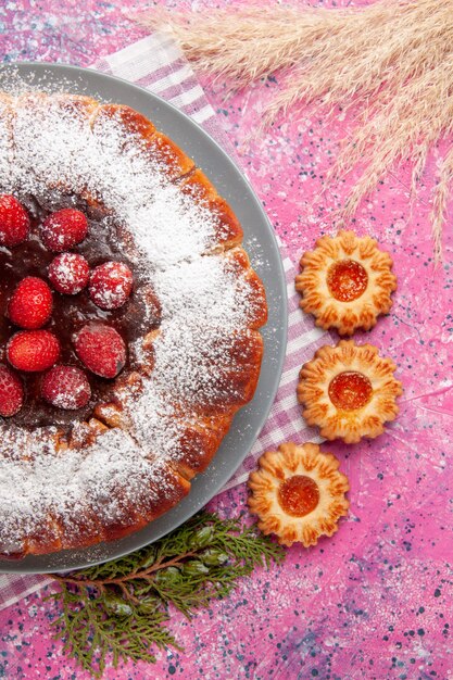 Draufsicht köstlicher Erdbeerkuchenzucker pulverisiert mit kleinen Keksen auf rosa Hintergrundkuchen süßer Keksplätzchentee