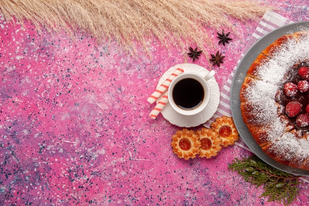 Draufsicht köstlicher Erdbeerkuchenzucker pulverisiert mit Tasse Tee und Keksen auf dem hellrosa Hintergrundkuchen süßer Keksplätzchentee