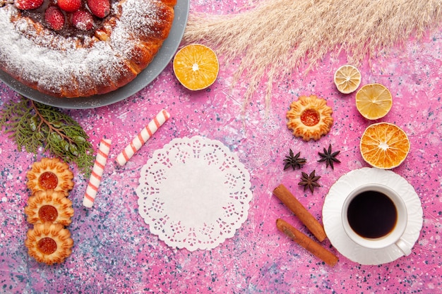 Draufsicht köstlicher Erdbeerkuchenzuckerkuchenpulver mit Keksen und Tasse Tee auf dem rosa Schreibtischkuchen süßer Zuckerplätzchenkuchen