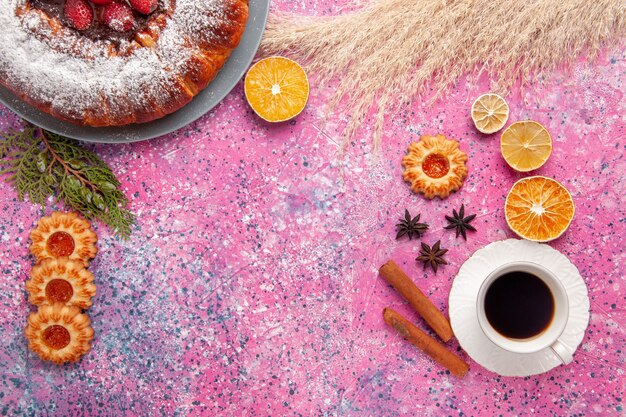 Draufsicht köstlicher Erdbeerkuchenzuckerpulverkuchen mit Keksen und Tasse Tee auf rosa Hintergrundkuchen süßer Zuckerplätzchenkuchen