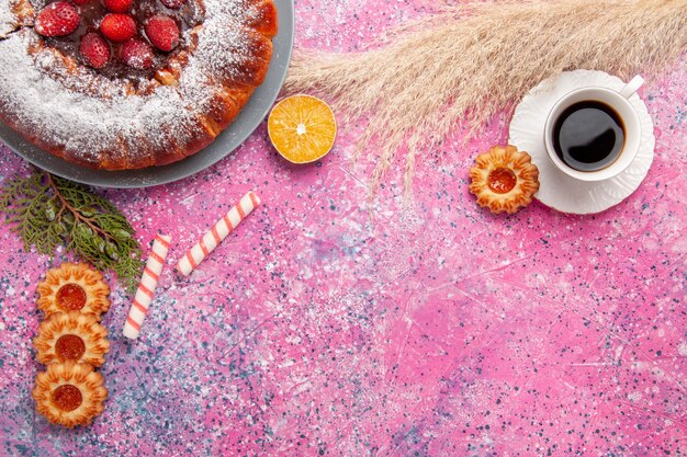 Draufsicht köstlicher Erdbeerkuchenzuckerpulverkuchen mit Keksen und Tasse Tee auf rosa Schreibtischkuchen süßer Zuckerplätzchenkuchen