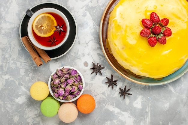 Draufsicht köstlicher fruchtiger Kuchen mit gelbem Sirup und Tasse Tee auf weißem Oberflächenkuchenkeks süßer Zucker backen Teekekse