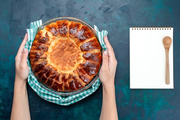 Draufsicht köstlicher gebackener Kuchen rund geformte süße innere Glaspfanne auf dem hellblauen Schreibtisch.