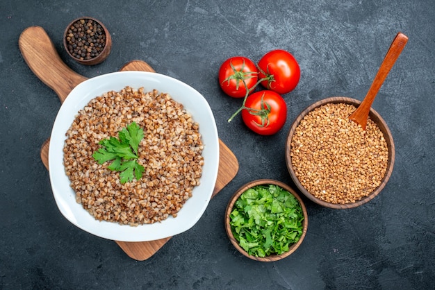 Kostenloses Foto draufsicht köstlicher gekochter buchweizen mit frischen tomaten und grüns auf dem grauen raum