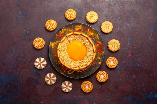 Draufsicht köstlicher gelber Kuchen cremiges Dessert mit Keksen auf der dunklen Oberfläche