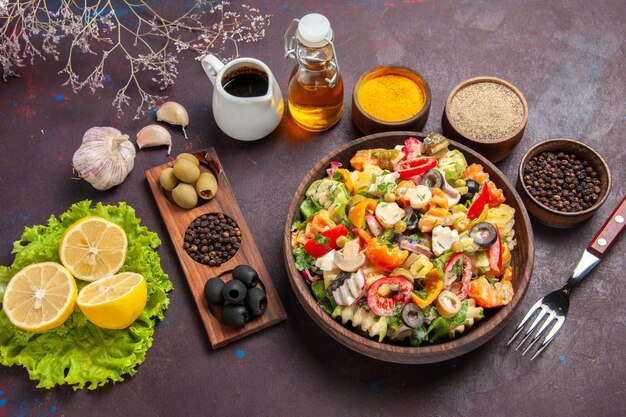 Draufsicht köstlicher Gemüsesalat mit geschnittenen Tomaten, Oliven und Pilzen auf dunklem Hintergrund