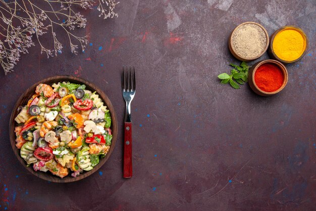 Draufsicht köstlicher Gemüsesalat mit verschiedenen Gewürzen auf dunklem Hintergrund Gesundheit Gemüsediät-Mittagssalat lunch