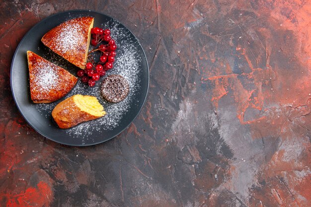 Draufsicht köstlicher geschnittener Kuchen mit roten Beeren auf dem dunklen Tisch süßer Kuchenkuchen