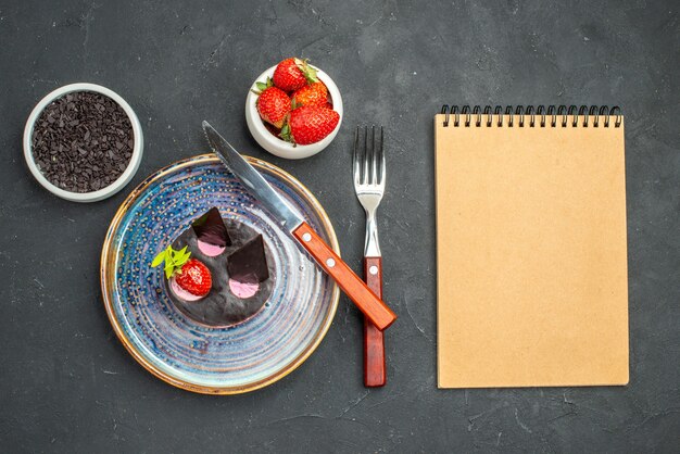 Draufsicht köstlicher Käsekuchen mit Erdbeeren und einem Messer auf Tellerschüsseln mit Erdbeeren auf dunklem, isoliertem Hintergrund