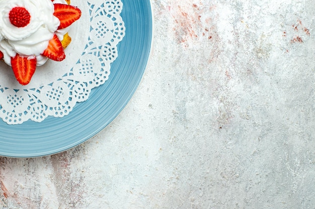 Draufsicht köstlicher kleiner kuchen mit sahne und erdbeeren auf weißem schreibtisch