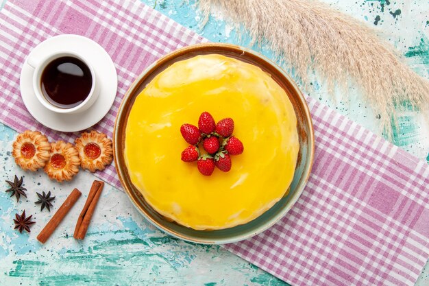 Draufsicht köstlicher Kuchen mit gelben Sirup frischen roten Erdbeeren und Tasse Tee auf blauer Oberfläche Kekskuchen backen süßen Zucker