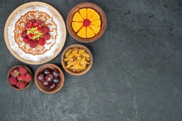 Draufsicht köstlicher Kuchen mit Himbeeren und Früchten auf dem grauen Hintergrund