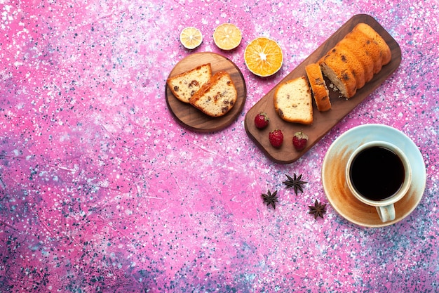 Draufsicht köstlicher Kuchen süß und lecker geschnitten mit einer Tasse Tee auf dem rosa Schreibtisch.