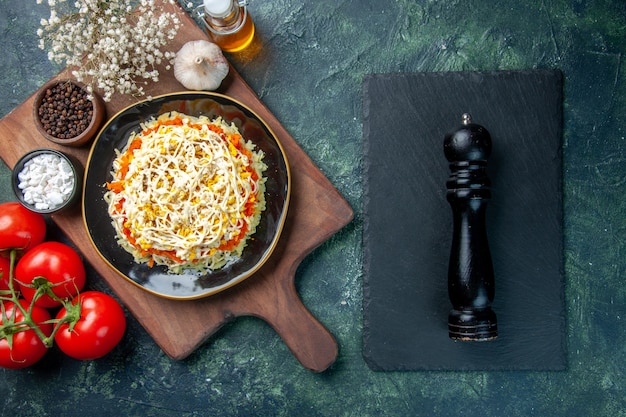 Draufsicht köstlicher Mimosensalat innerhalb Platte mit roten Tomaten auf dunkelblauem Hintergrund