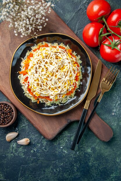 Draufsicht köstlicher Mimosensalat innerhalb Platte mit roten Tomaten auf dunkelblauem Hintergrund