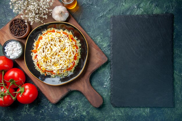 Draufsicht köstlicher Mimosensalat innerhalb Platte mit roten Tomaten auf dunkelblauem Hintergrund