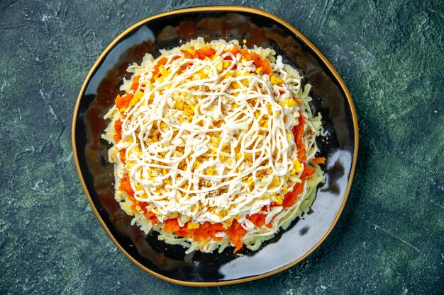 Draufsicht köstlicher Mimosensalat mit Eiern Kartoffel und Huhn innerhalb Platte auf dunkelblauem Hintergrund