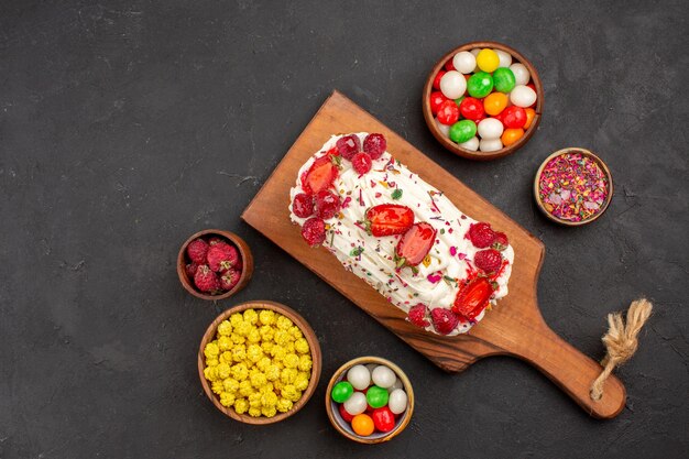 Draufsicht köstlicher Obstkuchen mit Früchten und Süßigkeiten auf dunklem Hintergrund Kuchenplätzchen süßer Kekskuchentee