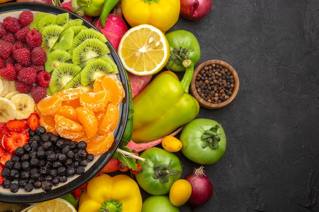 Draufsicht köstlicher Obstsalat im Teller mit frischen Früchten auf dem exotischen reifen Diätfoto des grauen tropischen Obstbaums