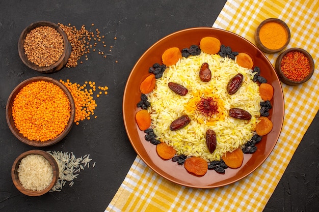 Draufsicht köstlicher Plov mit verschiedenen Rosinen auf dem dunklen Boden, der Essen Ostreis-Abendessen kocht?