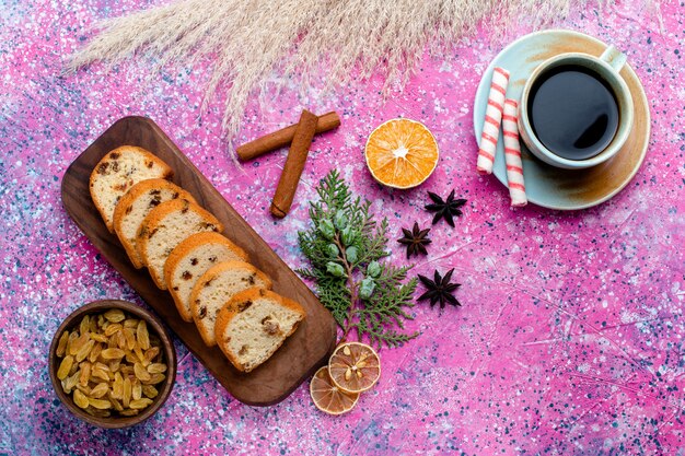 Draufsicht köstlicher Rosinenkuchen geschnittener Kuchen mit Kaffee auf dem rosa Schreibtisch backen Kuchenzucker-süßer Keksplätzchen