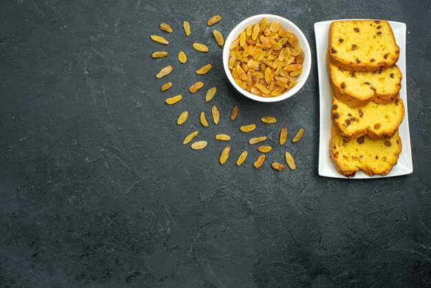 Draufsicht köstlicher Rosinenkuchen mit frischen Rosinen auf dunkler Oberfläche süßer Kuchenkeks-Teekuchen-Tee