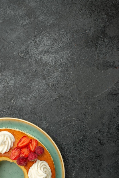 Kostenloses Foto draufsicht köstlicher runder kuchen mit früchten und sahne auf dunklem schreibtischtee-zucker-keks-keks-kuchen-torte süß