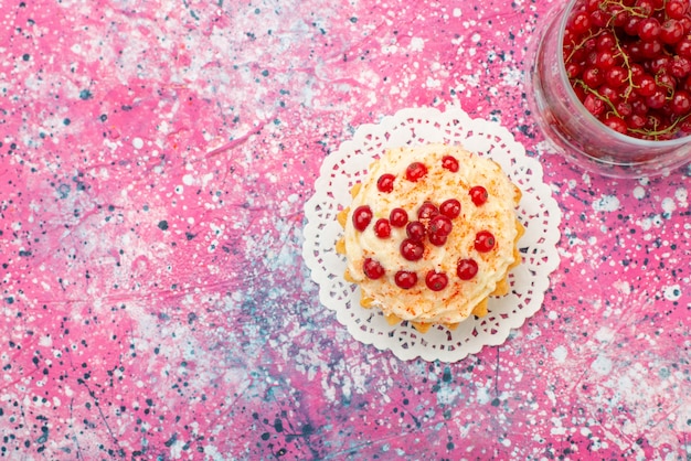 Draufsicht köstlicher runder Kuchen mit Sahne und frischen roten Preiselbeeren auf dem lila Bodenzucker