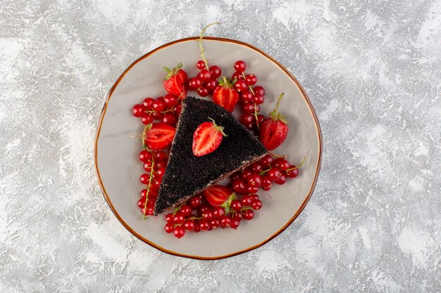 Draufsicht köstlicher Schokoladenkuchen geschnitten mit Schoko-Sahne und frischen roten Preiselbeeren auf dem hellen Hintergrundkuchen-Keksteig backen süß