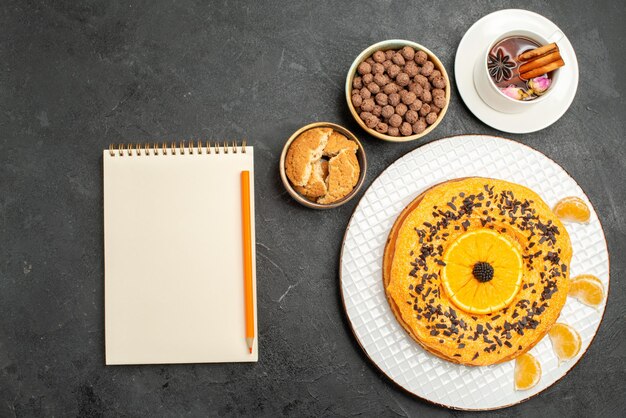 Draufsicht köstlicher süßer Kuchen mit Tasse Tee auf dunkelgrauer Oberfläche Cookie Pie Keks Dessert Tee Kuchen