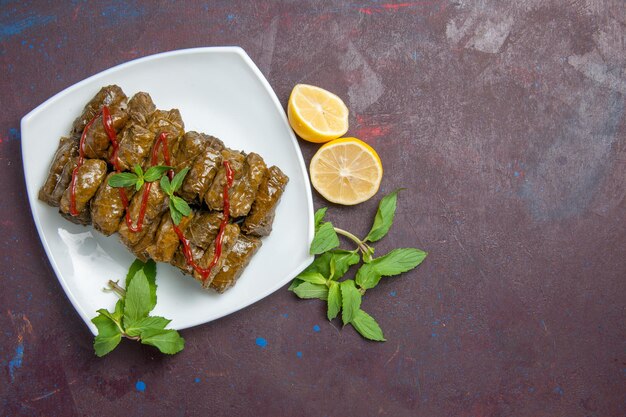 Draufsicht köstliches Blatt-Dolma-Fleischgericht innerhalb der Platte auf dunklem Hintergrundtellerblatt-Abendessen-Essensfleisch