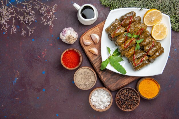 Draufsicht köstliches Blatt-Dolma mit Zitronenscheiben und Gewürzen auf dem dunklen Hintergrund Fleischgericht Blatt Abendessen Essen