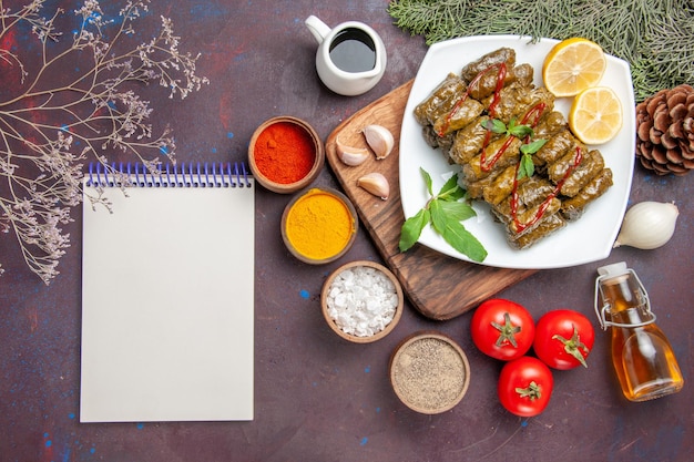 Draufsicht köstliches Blatt-Dolma mit Zitronenscheiben und Gewürzen auf dem dunklen Hintergrund-Mahlzeitgericht Blattfleisch-Abendessen-Essen