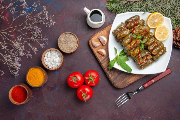 Draufsicht köstliches Blatt-Dolma mit Zitronenscheiben und Gewürzen auf dunklem Hintergrundgericht Blattfleisch Abendessen Essen