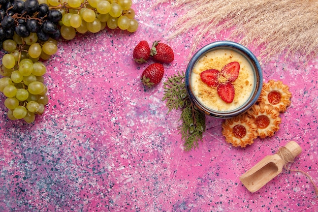 Draufsicht köstliches cremiges Dessert mit frischen grünen Trauben und Keksen auf dem hellrosa Hintergrunddessert Eisbeerencreme süße Frucht