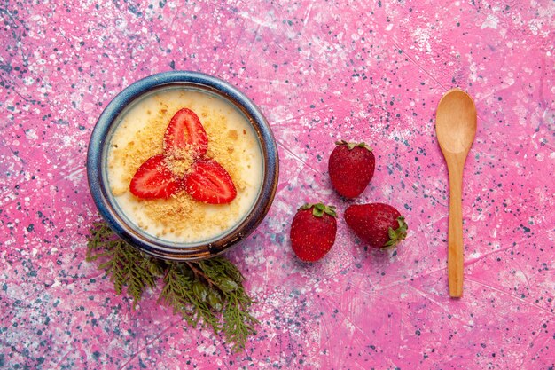 Draufsicht köstliches cremiges Dessert mit rot geschnittenen Erdbeeren auf dem hellrosa Hintergrunddessert-Eiscremefarbe süßes Eis