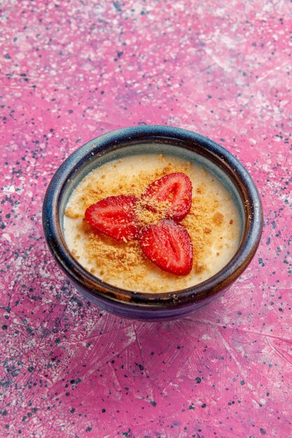 Draufsicht köstliches cremiges Dessert mit rot geschnittenen Erdbeeren auf hellrosa Hintergrunddessert-Eiscreme süße Beerenfrucht