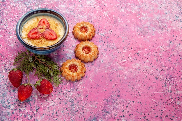 Draufsicht köstliches cremiges Dessert mit rot geschnittenen Erdbeeren und Keksen auf dem hellrosa Hintergrunddessert-Eiscremefarbe süßes Eis