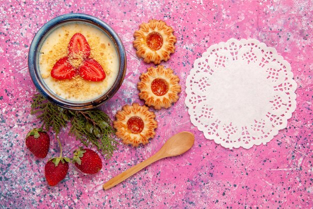 Draufsicht köstliches cremiges Dessert mit rot geschnittenen Erdbeeren und kleinen Keksen auf rosa Hintergrunddessert-Eiscremefarbe süßes Eis