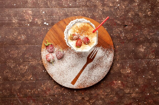 Draufsicht köstliches Dessert mit Erdbeeren auf braunem Schreibtisch