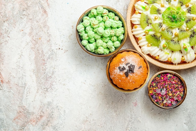 Kostenloses Foto draufsicht köstliches dessert mit geschnittenen kiwis und bonbons auf weißem hintergrund kuchen keks dessert sahne fruchtsüßigkeit