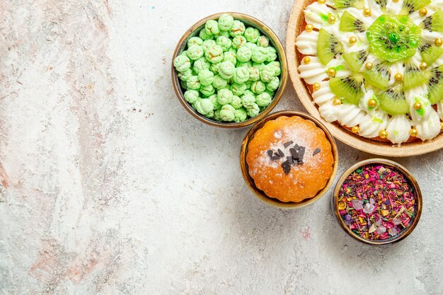 Draufsicht köstliches Dessert mit geschnittenen Kiwis und Bonbons auf weißem Hintergrund Kuchen Keks Dessert Sahne Fruchtsüßigkeit