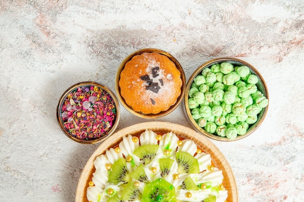 Draufsicht köstliches Dessert mit geschnittenen Kiwis und Süßigkeiten auf weißem Hintergrund Dessertcreme Früchte Kuchen Süßigkeiten