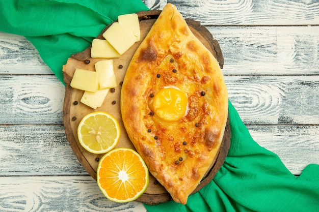 Draufsicht köstliches Eierbrot, das mit Käse auf einem rustikalen grauen Schreibtisch gebacken wird